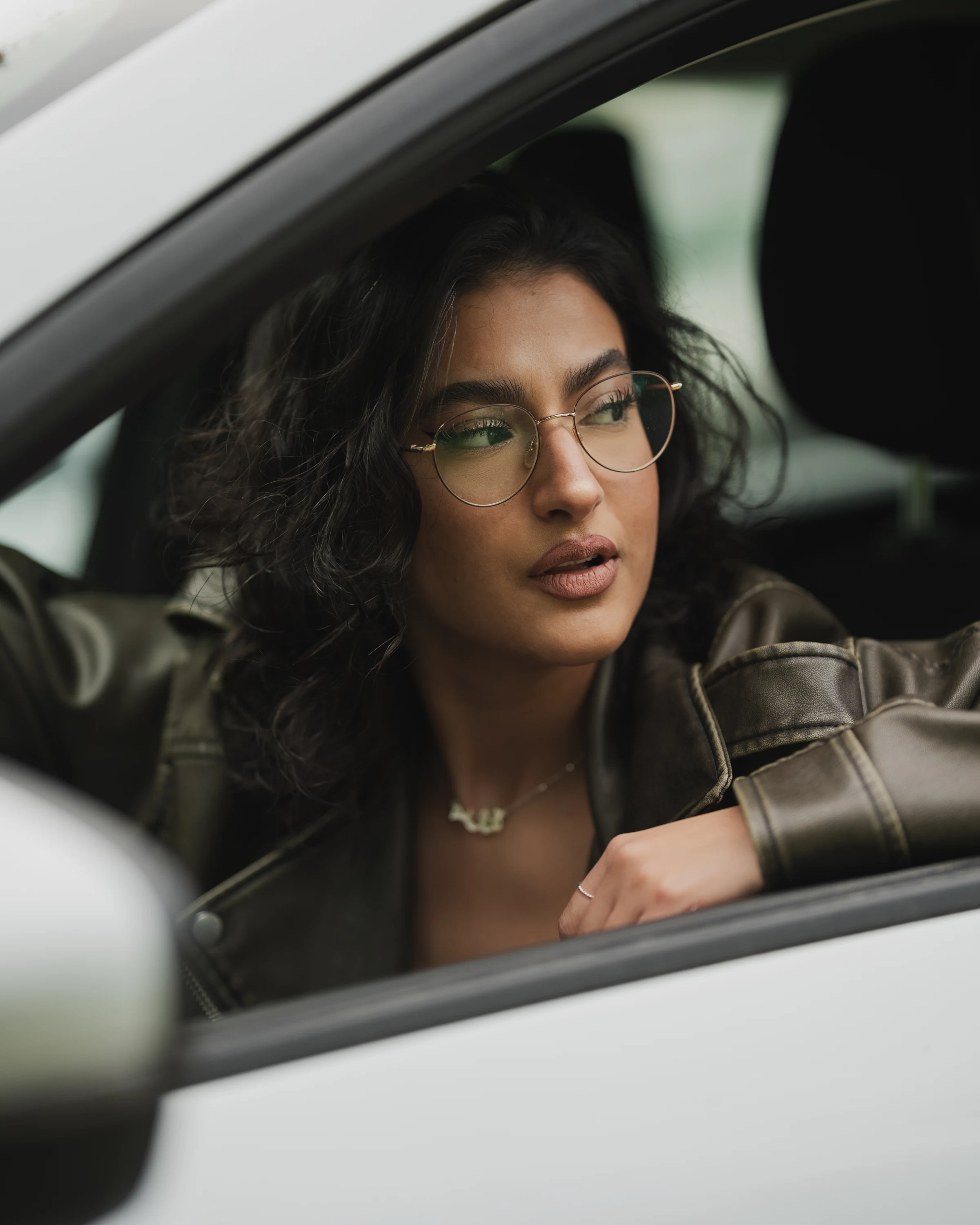 Editorial portrait of a woman photographed through a car window